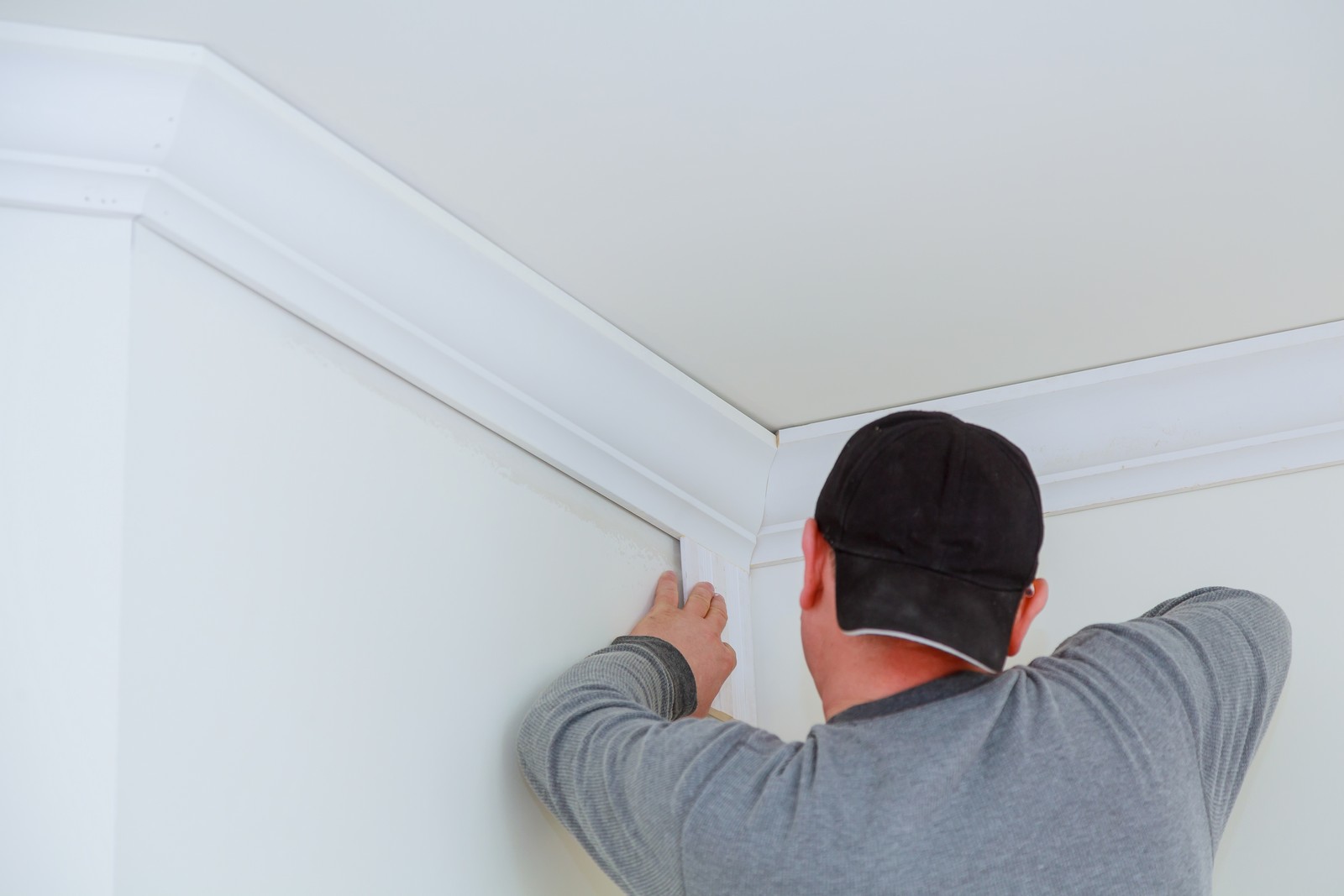 Sure, here it is:
"A high-resolution image showcasing the installation of an intricately designed ceiling. The photograph focuses on a section of the ceiling where artisans are carefully fitting decorative cornices. The ceiling features elaborate plasterwork, including ornate floral patterns and geometric motifs, creating a visually stunning effect. The workers, wearing white overalls and safety helmets, use precise tools to ensure perfect alignment of the detailed elements. Scaffolding and ladders are visible, providing access to the higher areas. The setting is well-lit, highlighting the craftsmanship and attention to detail involved in this specialised ceiling installation."